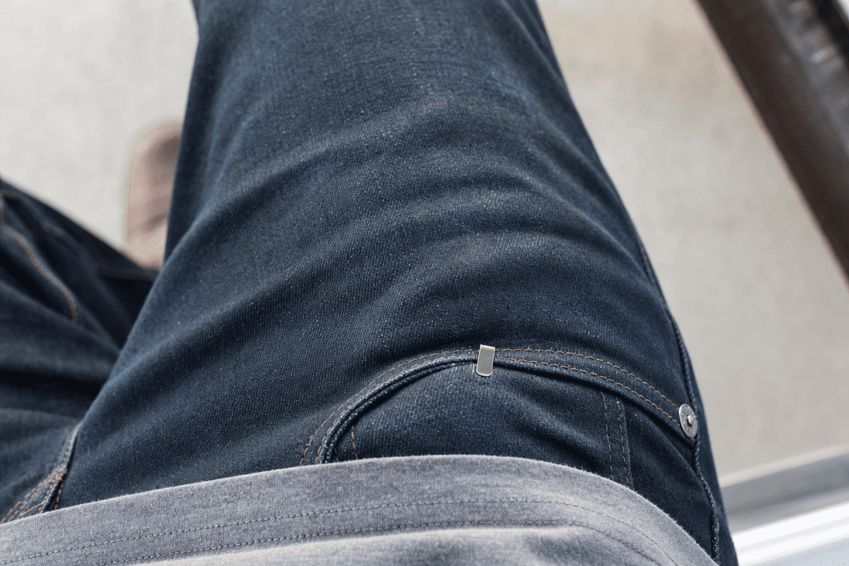 A folding knife riding deep in a jeans pocket with only the clip visible above the pocket line