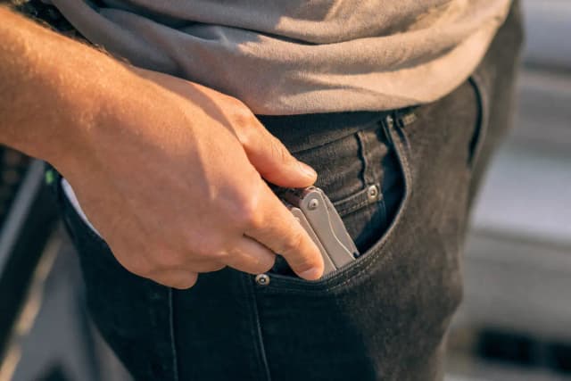 Person pulling a compact tool from a denim jeans pocket — clean pocket carry